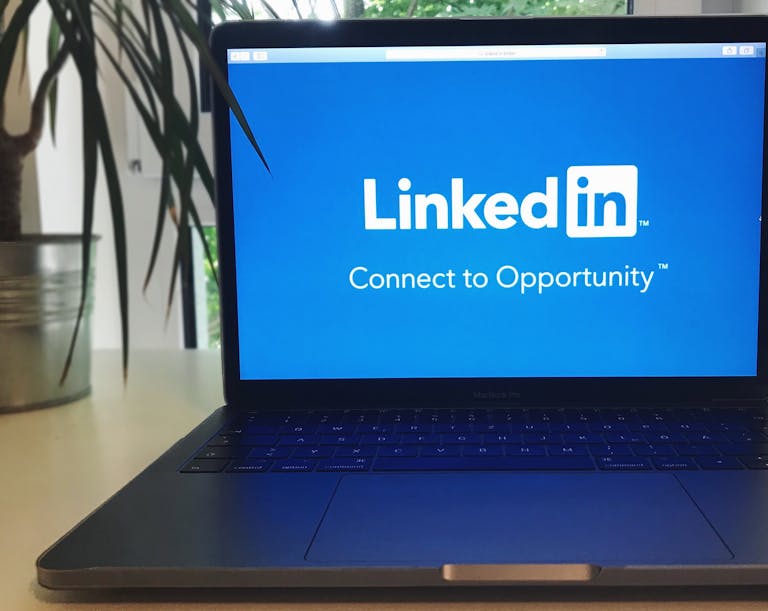 A laptop screen displaying the LinkedIn logo with the text 'Connect to Opportunity'.